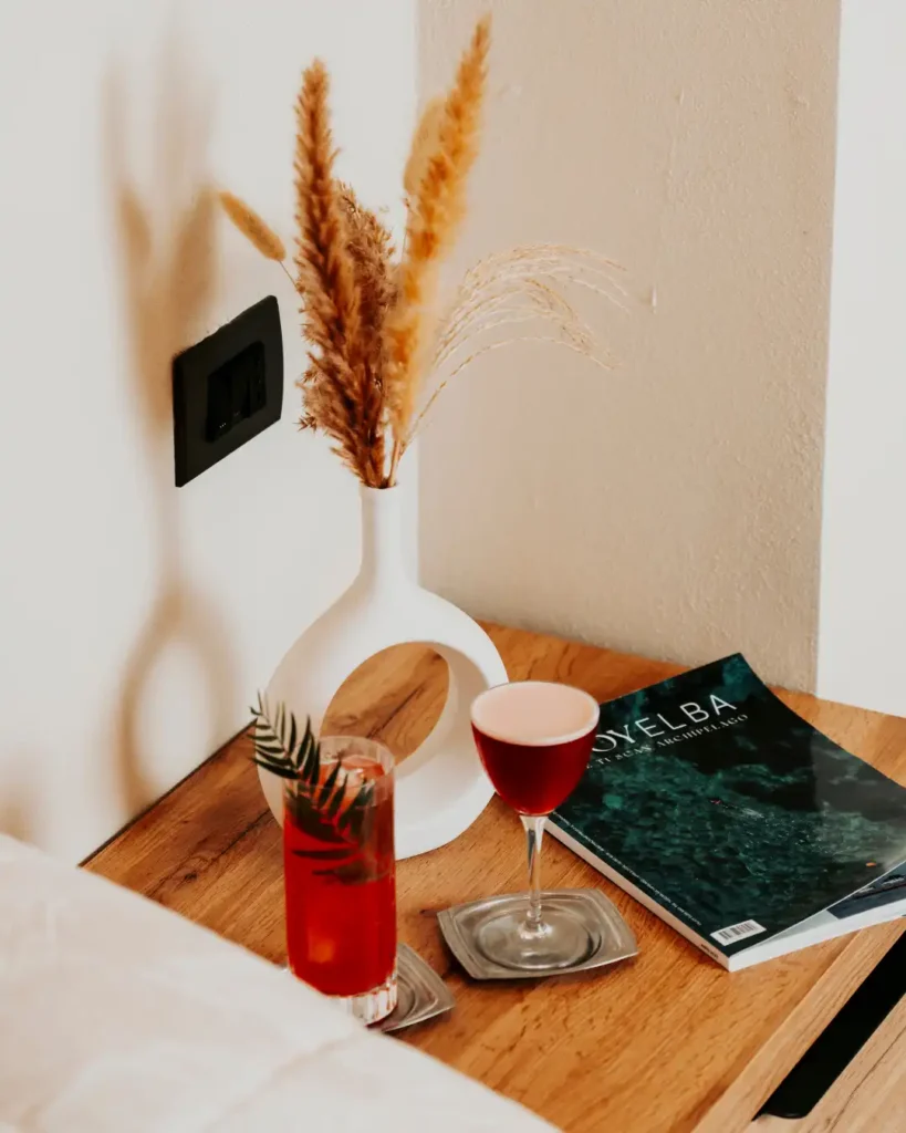 Dettaglio arredamento camera B&B Carosello: comodino con riviste e due cocktail colorati per un momento di relax all'Elba