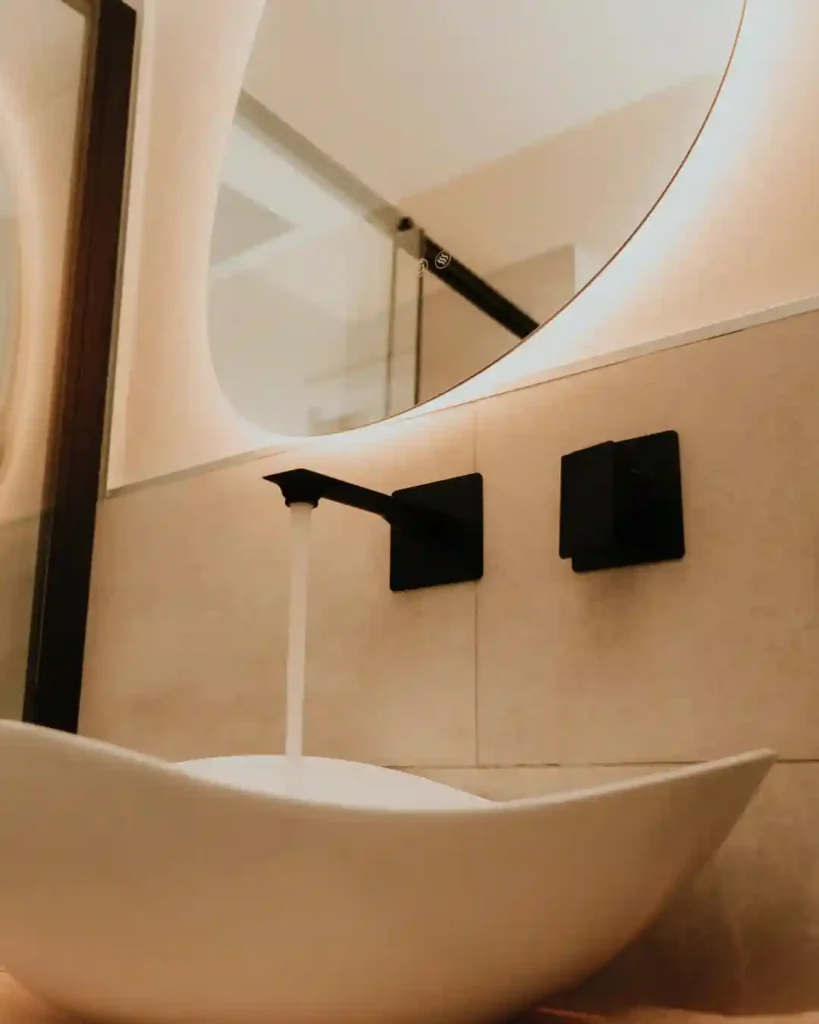 Bagno moderno al B&B Carosello: lavandino con specchio illuminato a LED e rubinetteria nera a muro all'Isola d'Elba.