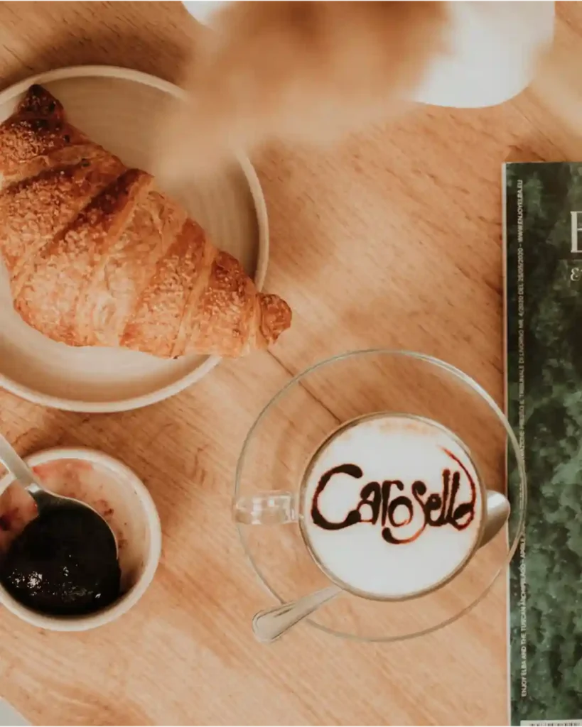 Eccellenza nell'accoglienza al B&B Carosello: cappuccino con logo personalizzato sulla schiuma, brioches fresche e marmellate all'Isola d'Elba.
