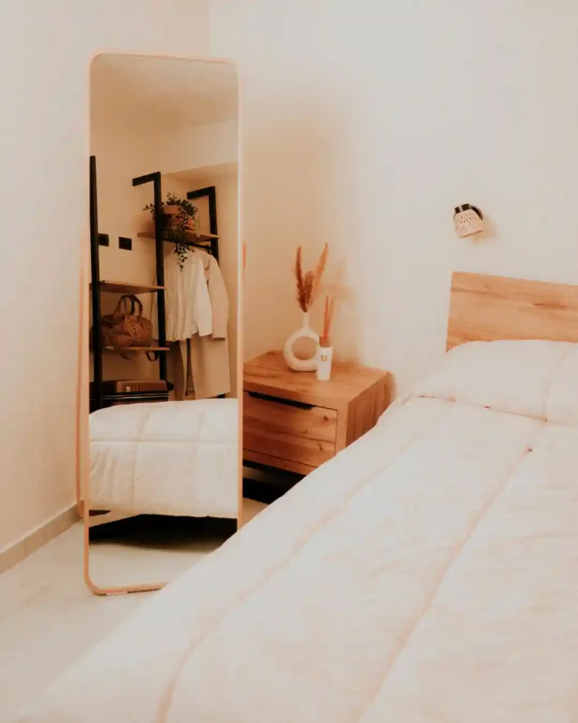 Arredamento moderno della camera al B&B Carosello: dettaglio letto, comodino e specchio da terra all'Isola d'Elba.